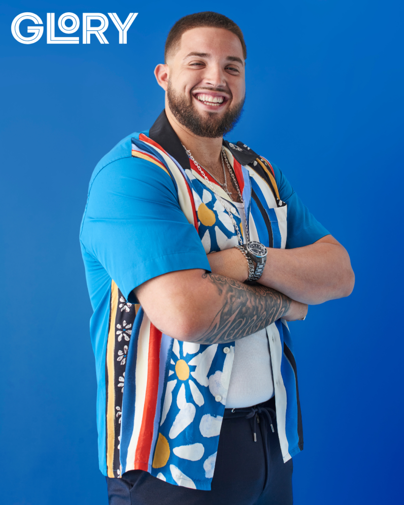 Alek Manoah with crossed arms and patterned shirt smiling against blue background