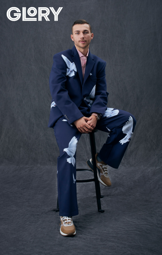 Michael Bunting sits on a stool for a portrait wearing a blue and white suit.